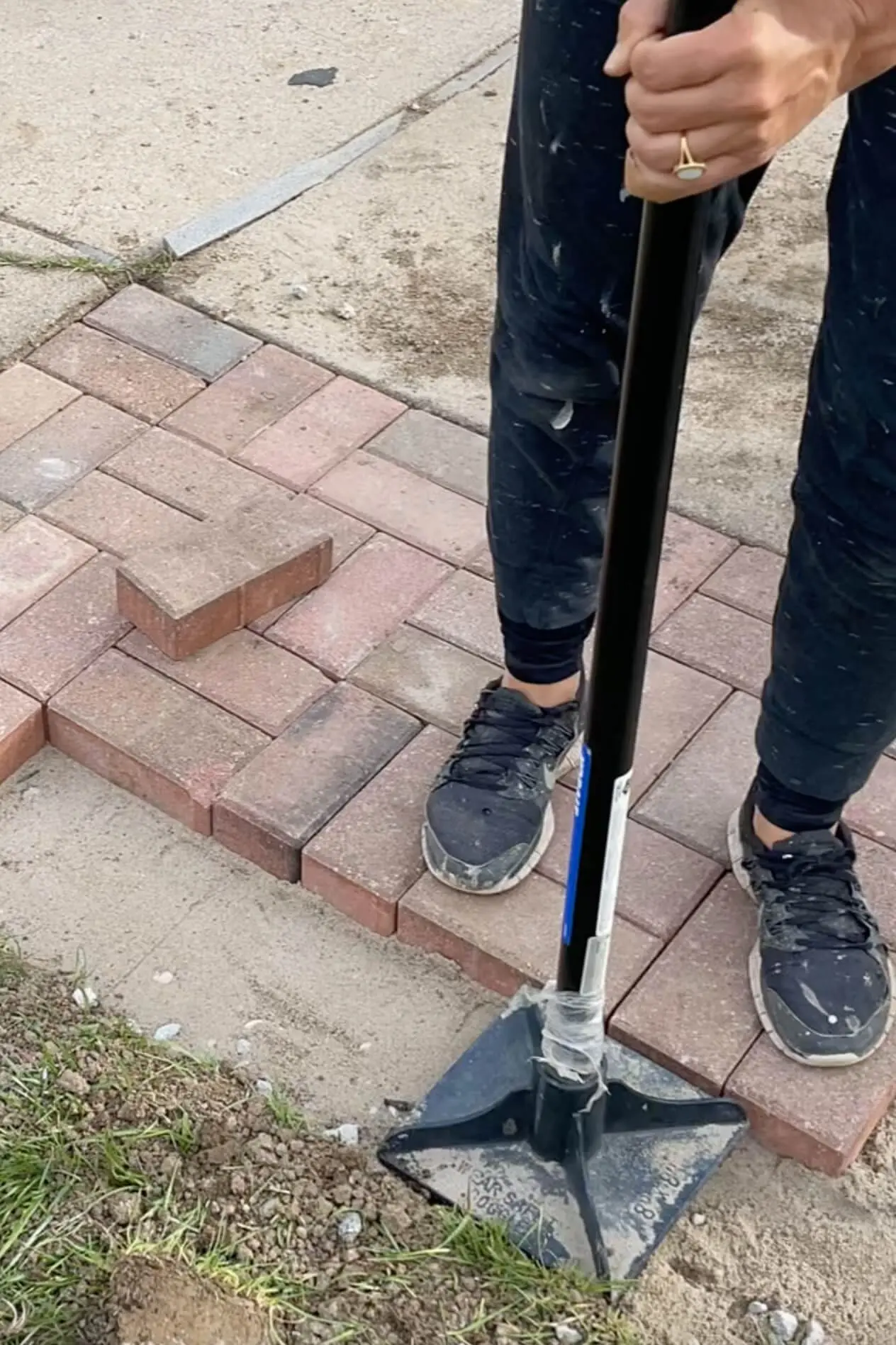 Tamping sand for DIY paver driveway extension.